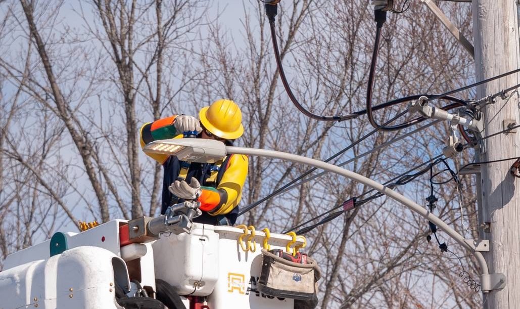 Lineworker in a bucket truck fitting a cobrahead streetlight, Augusta, ME