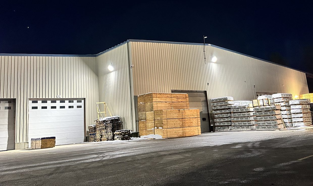 Boise Cascade distribution building at night with wall-mounted lights over stacked lumber, Greenland, NH