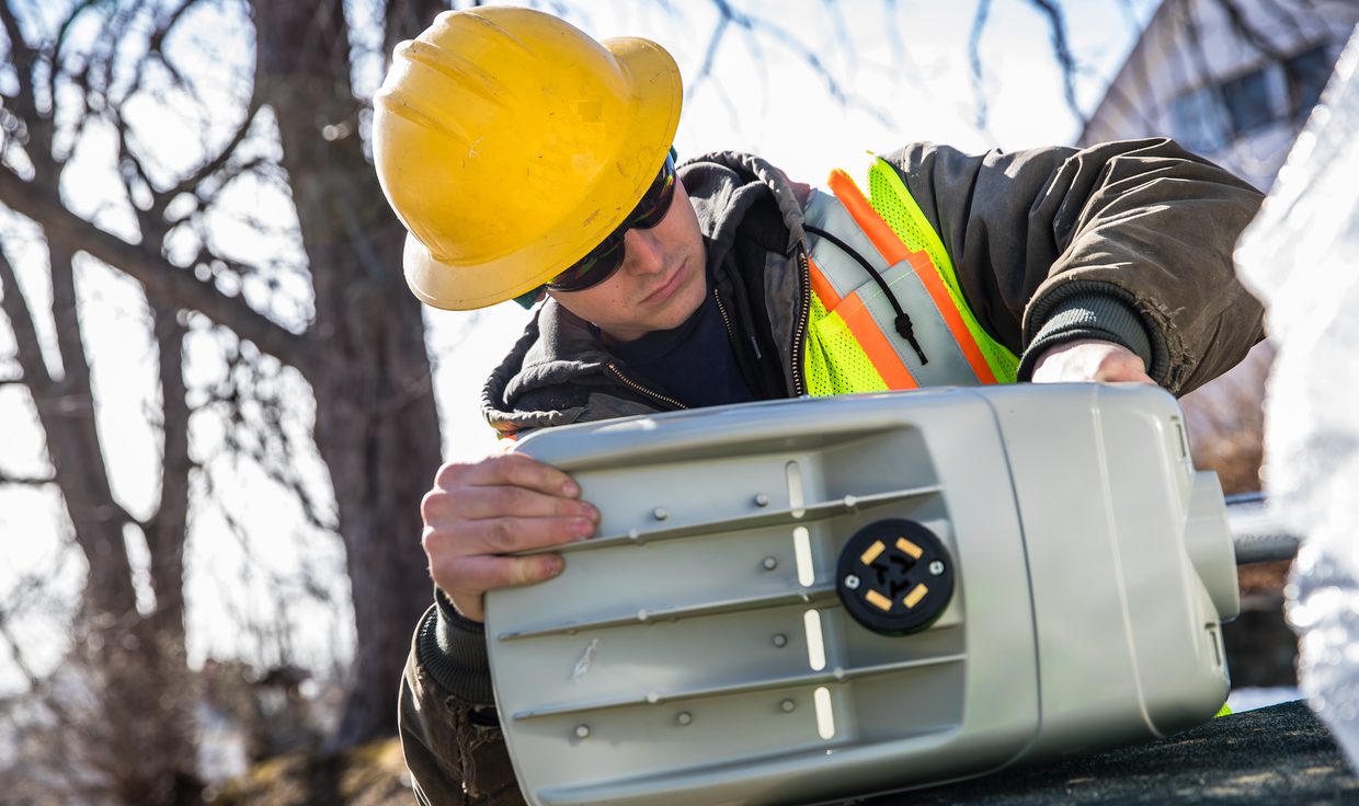 Crew member inspecting the underside of an LED cobrahead streetlight before installation, Eliot, ME