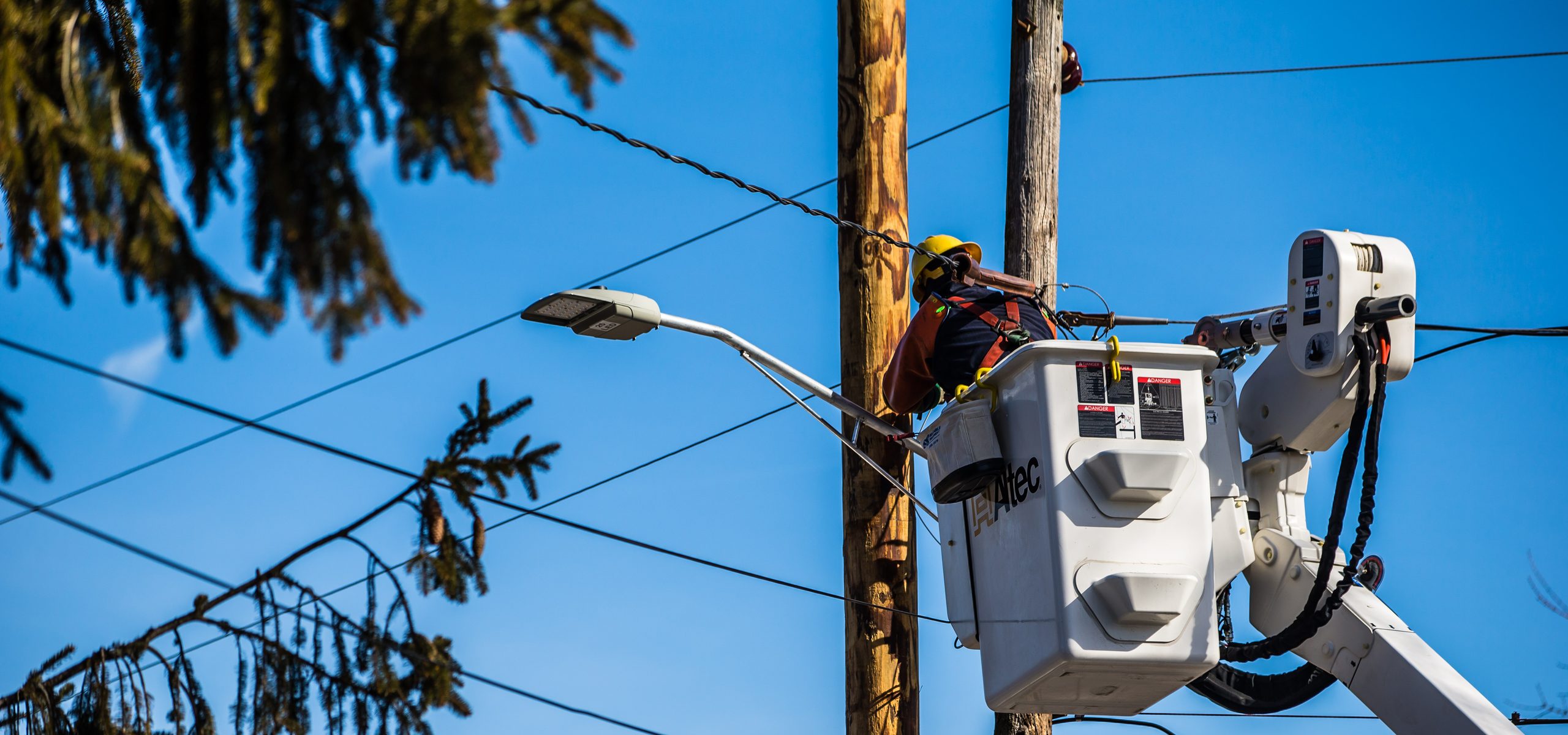 Lineworker in a bucket truck installing a streetlight on a utility pole, Eliot, ME