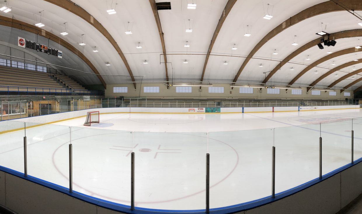 JFK Coliseum ice rink under LED fixtures between curved wood roof arches, Manchester, NH
