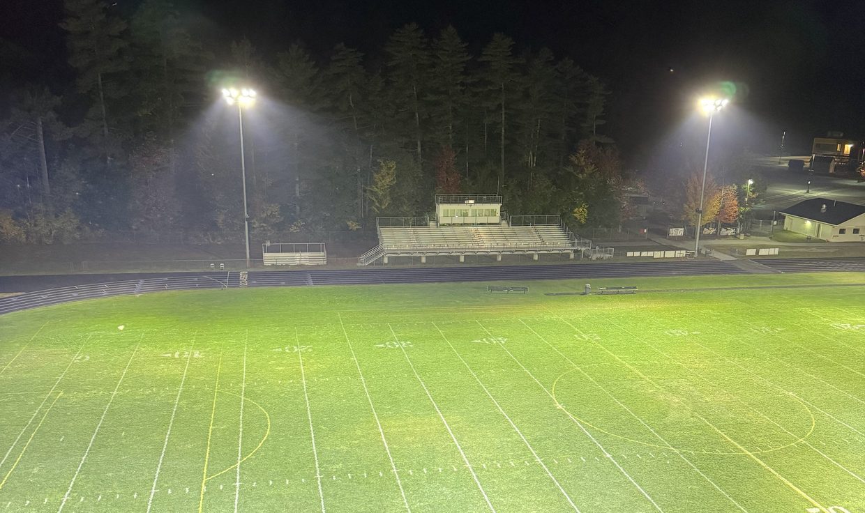 Elevated night view of the Kennett High School football field under LED pole lights, Conway, NH