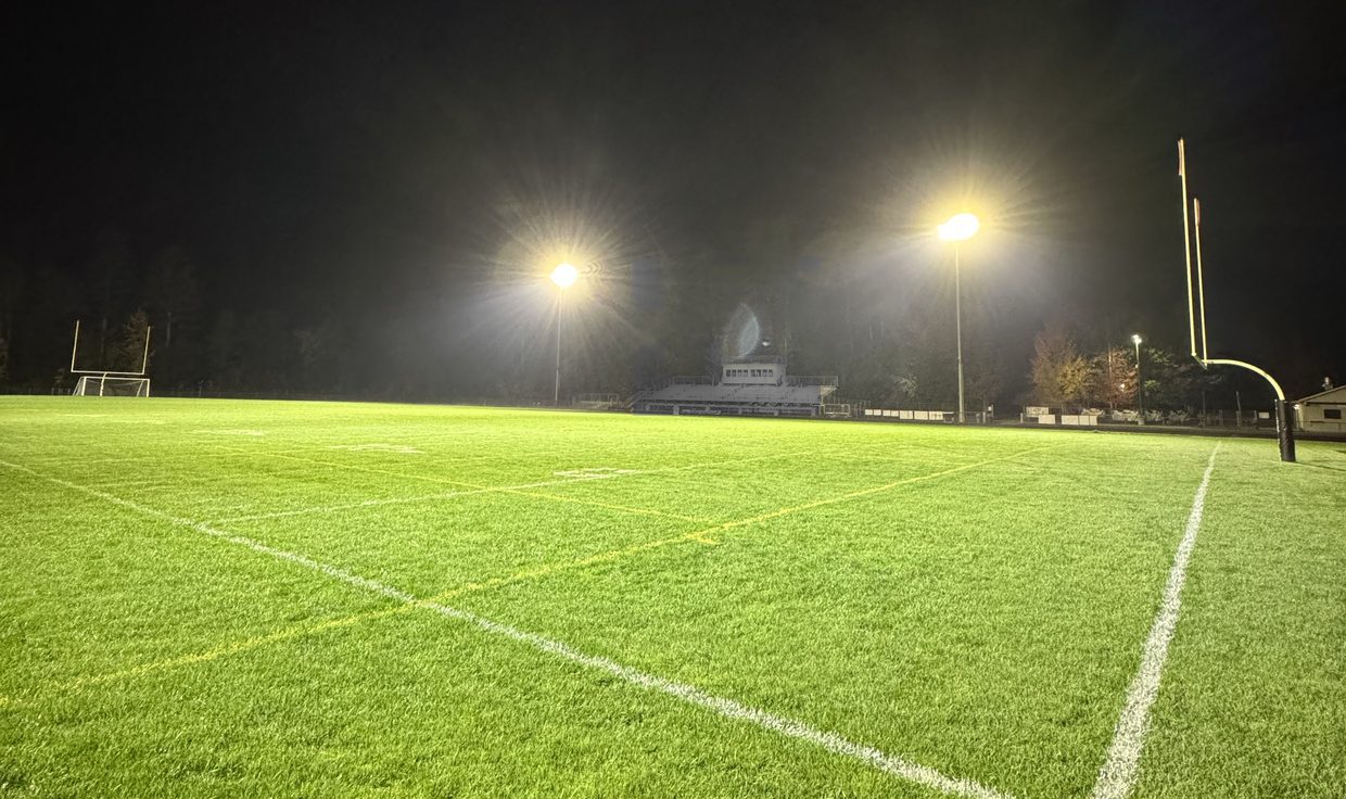 Corner field lines on the lit Kennett High School field at night, with two LED light poles beyond, Conway, NH