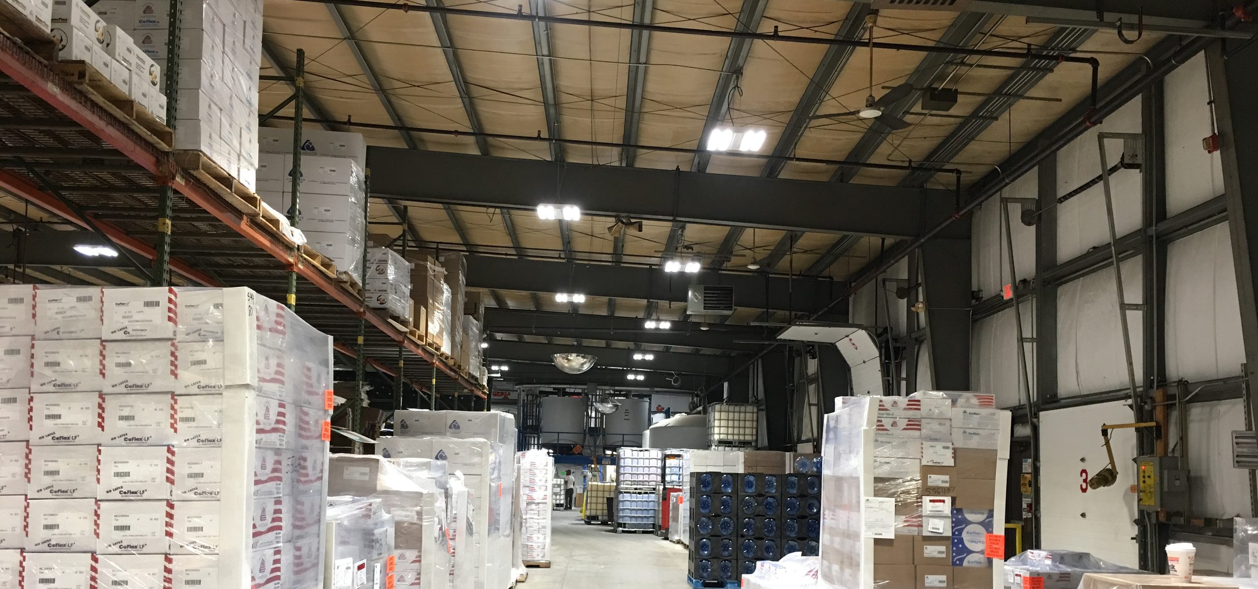 Milliken Healthcare warehouse aisle lined with pallets under LED high-bay fixtures, Salisbury, MA