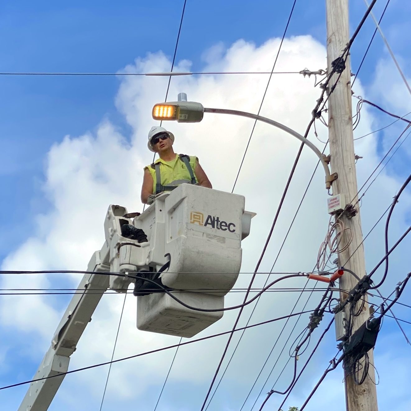 Lineworker beside a newly installed, lit LED cobrahead streetlight, Bristol, NH